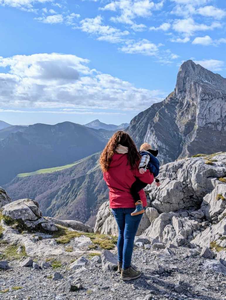 Mum holding toddler while looking out across the peaks of Picos de Europa.
