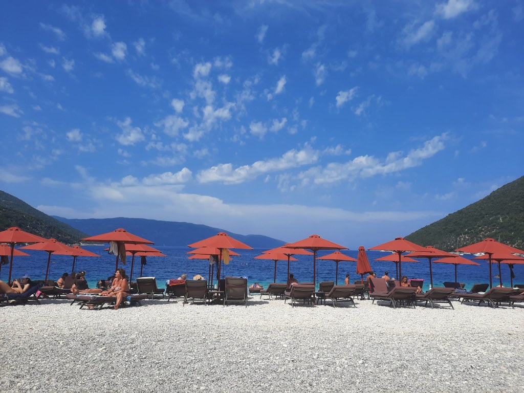Relaxing beach scene with loungers and turquoise sea at Antisamos Beach