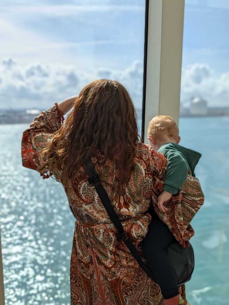 Parent and child looking out the window of a sunny ferry crossing, Dover-Calais route