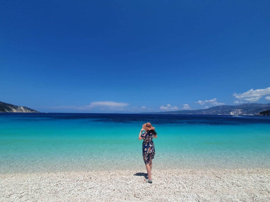 Woman standing with back to camera, gazing at turquoise sea from Fteri Beach