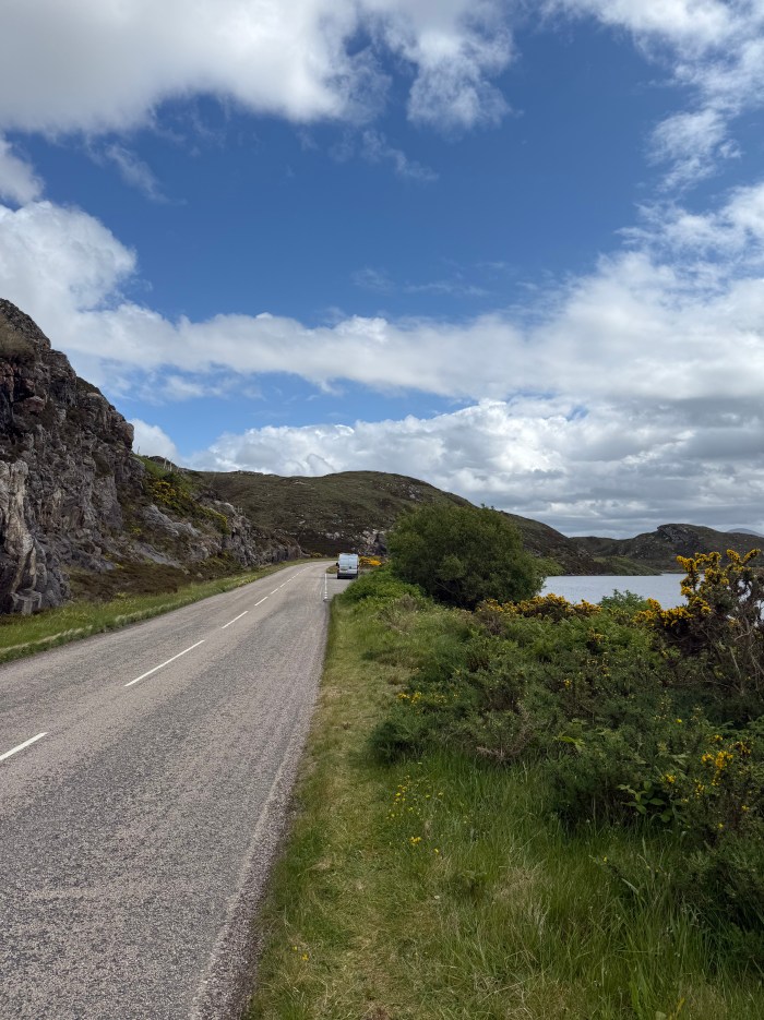 Campervan surrounded by scenic Scottish Highlands with mountains in the background