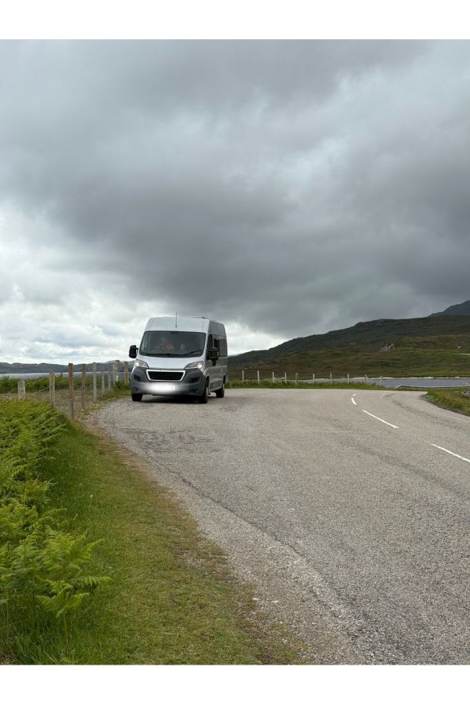 Campervan parked on a winding road in the Scottish Highlands