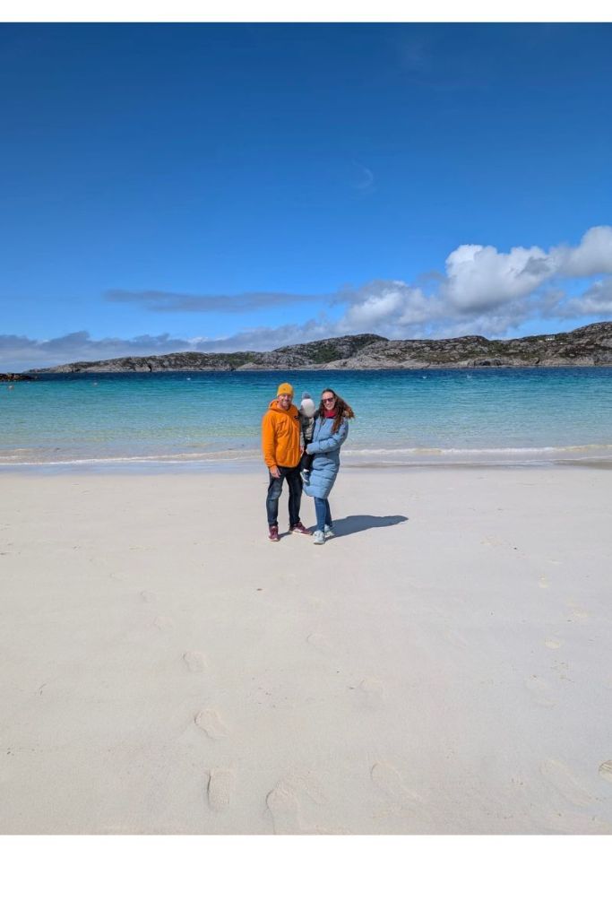 Family moment on a stunning NC500 white-sand beach Family standing on a white-sand Scottish beach wearing winter coats and hats