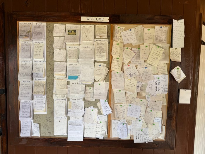 Wall of handwritten traveller notes inside cabin at Strathy Beach