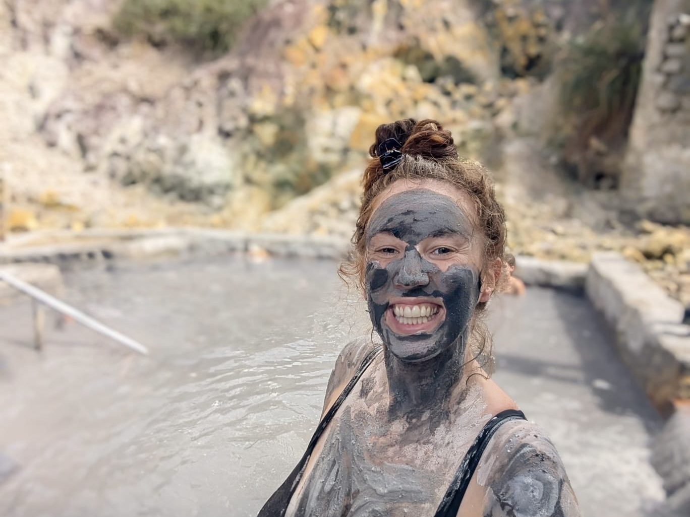 Woman covered in grey sulphur mud at the volcanic spa in Saint Lucia