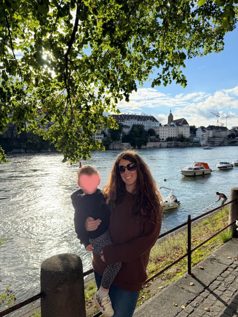 Mother and toddler smiling by the river in Basel, Switzerland.