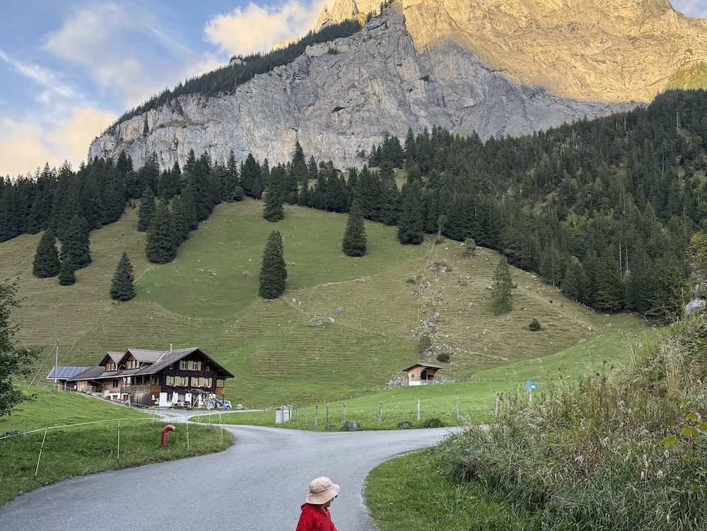 Toddler standing on a mountain road in Switzerland with peaks behind.