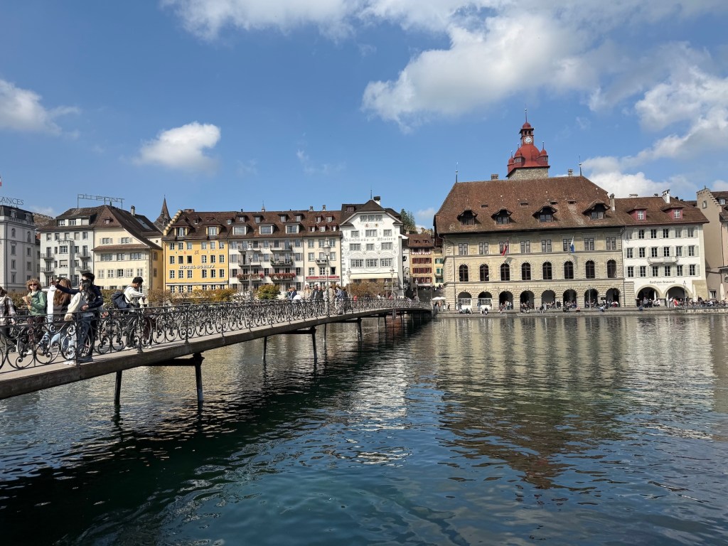 Scenic view of Lucerne’s lake, bridge, and colourful old town waterfront.