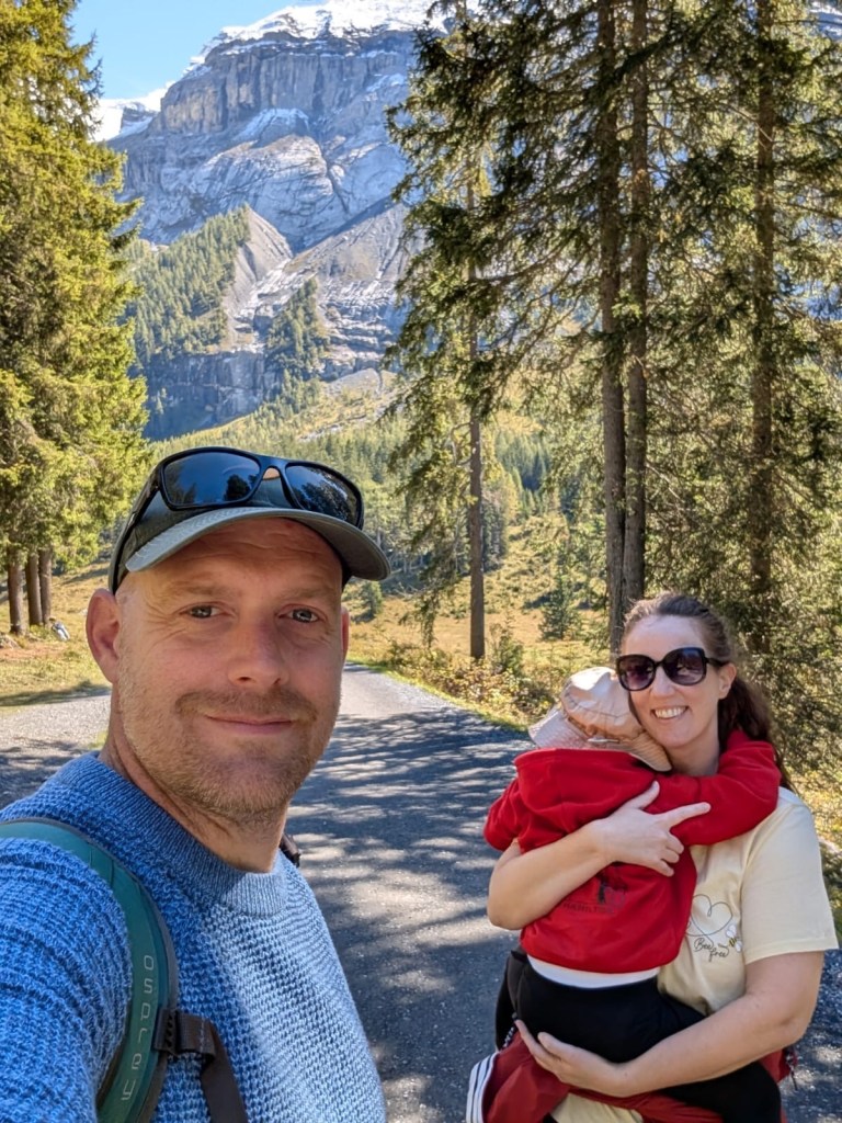 Family walking towards Oeschinensee Lake in Switzerland, carrying a toddler.