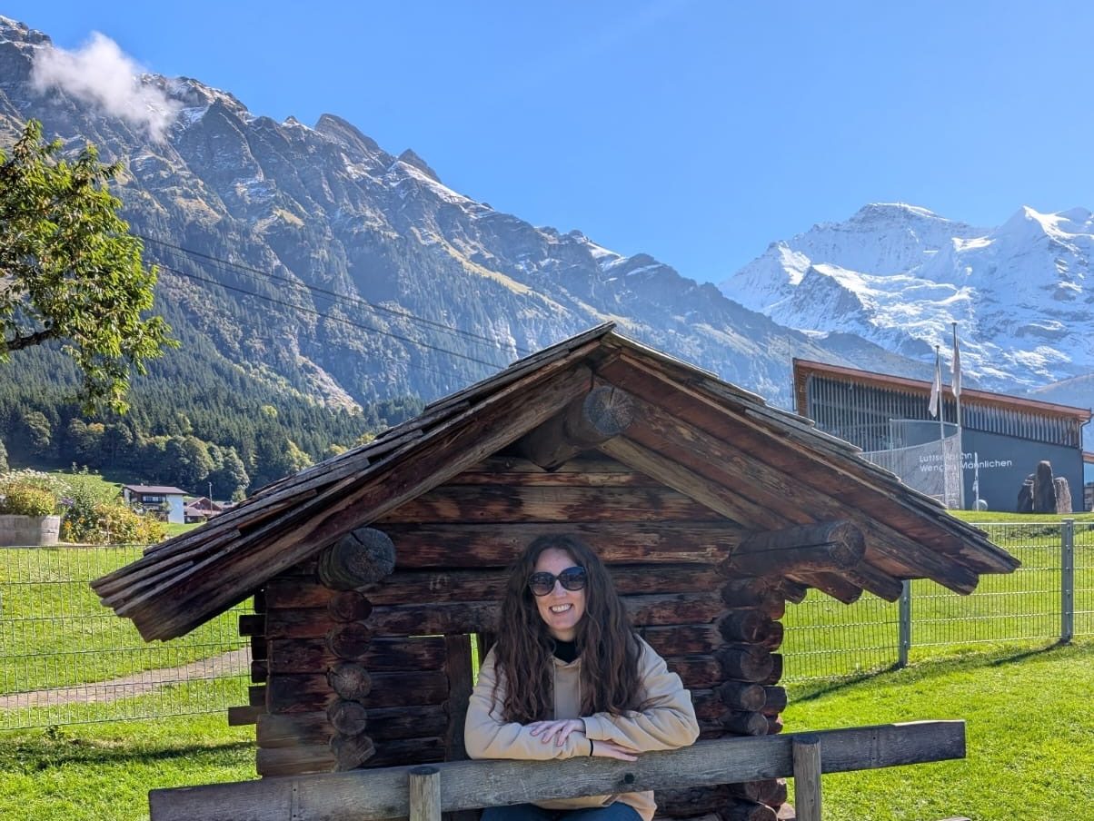 Woman inside a wooden playhouse with Swiss mountains behind.