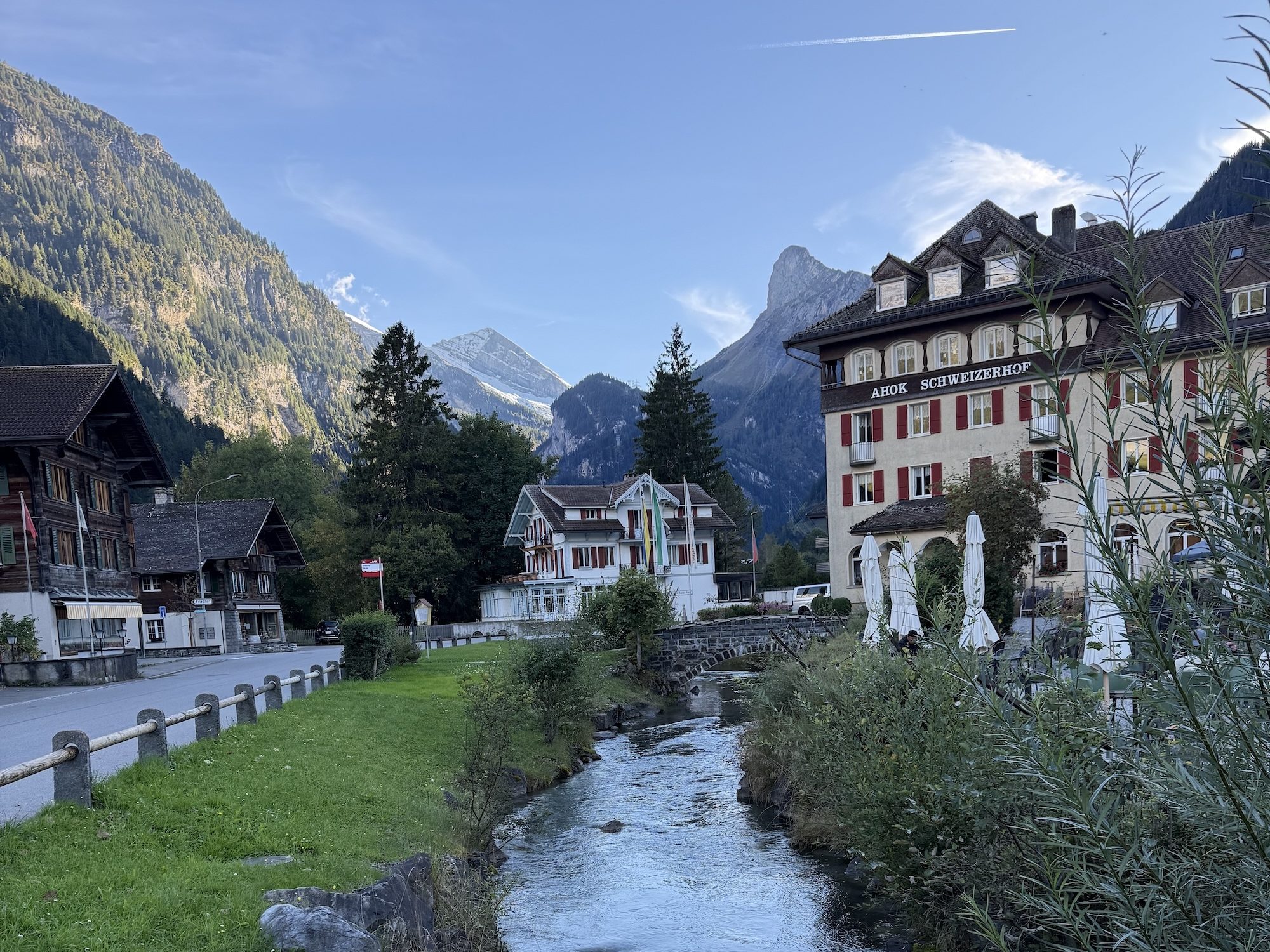 Traditional Swiss alpine village with a mountain backdrop and stream running through.