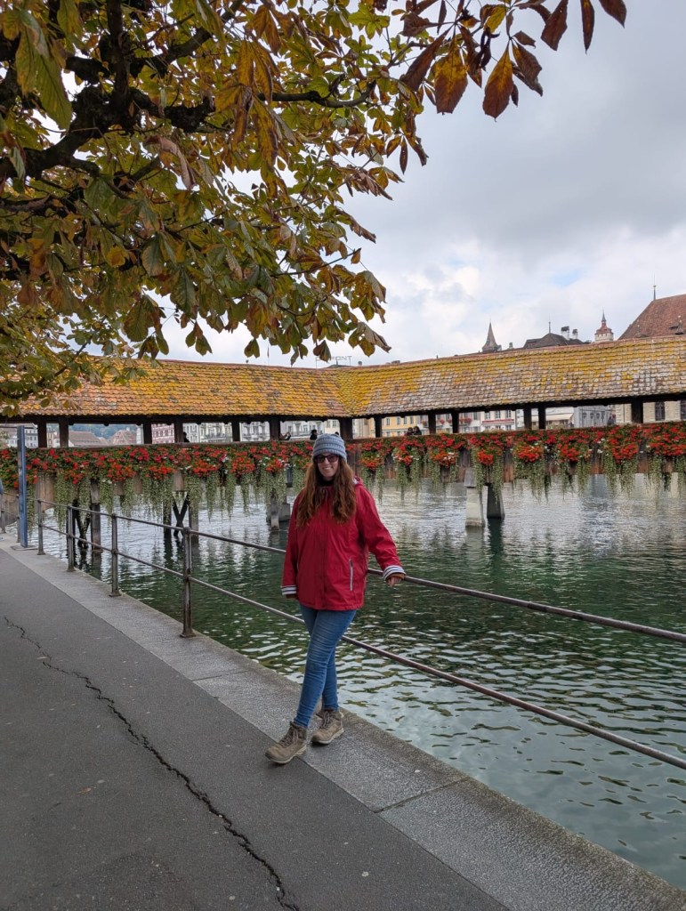 Woman standing by Lake Lucerne with the famous flower bridge in the background