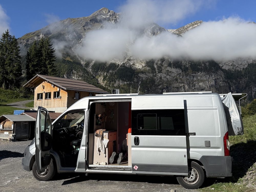 Campervan parked overnight with open doors and mountain views in Switzerland