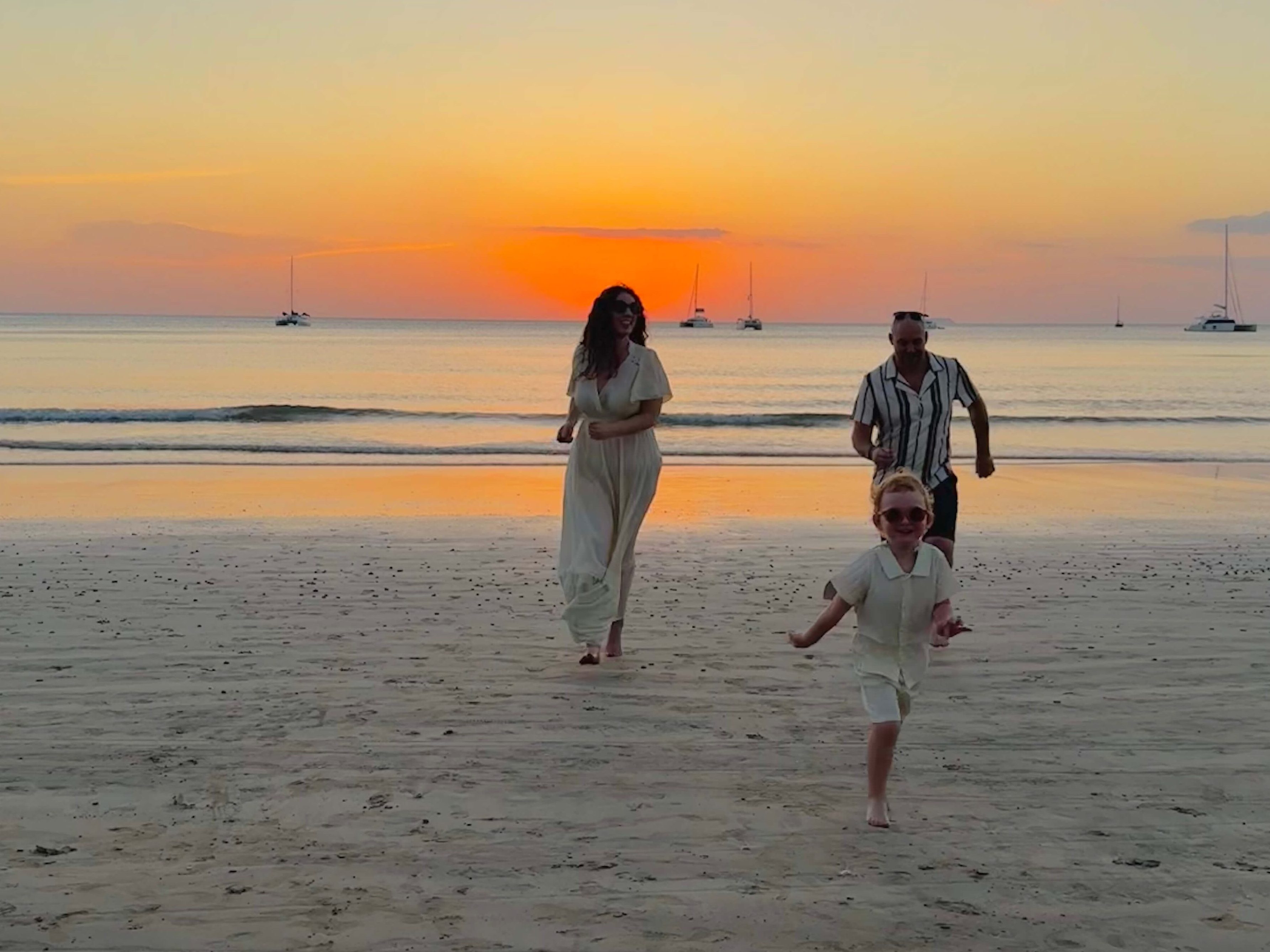 young family on the beach at sunset, running towards camera